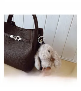 Détail d'un sac en cuir marron à motif litchi avec un charmant lapin en peluche doux