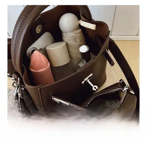 Vue de dessus montrant la grande capacité intérieure du sac seau en cuir marron avec objets