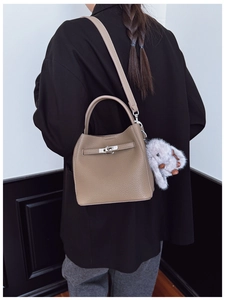 Détail du sac seau en cuir taupe avec fermoir tournant argenté et pendentif lapin