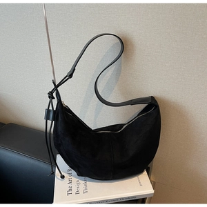 Detail of black suede crescent bag with side knot design and smooth metal zipper closure