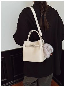 Détail du sac seau en cuir crème avec une breloque lapin en peluche mignonne