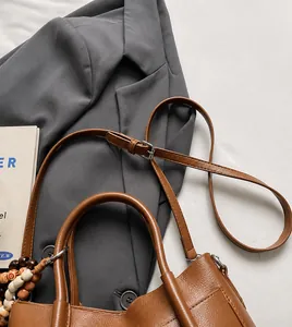 Détail de la bandoulière réglable en cuir et de la breloque en perles décoratives du sac à main