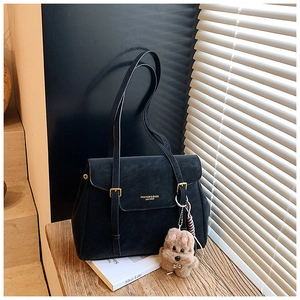 Détail du sac cabas en cuir noir avec boucle dorée et pendentif peluche chien marron