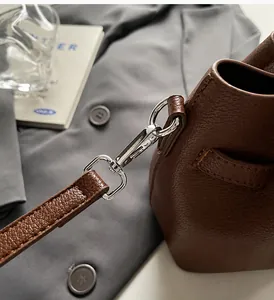 Détail du crochet en métal argenté et de la bandoulière en cuir grainé marron