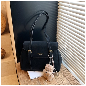 Détail du sac cabas en cuir mat noir avec fermeture à rabat et breloque chien mignonne