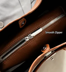 Détail de la fermeture éclair argentée et du cuir grainé du sac seau couleur caramel
