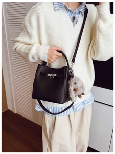 Détail du sac seau en cuir grainé noir avec boucle argentée et breloque lapin en peluche
