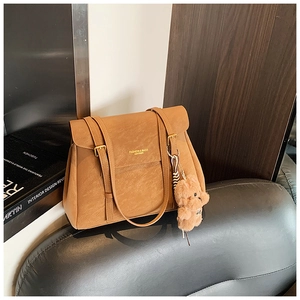 Détail du sac cabas en cuir caramel avec texture grainée et pendentif ours en peluche