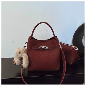 Vue détaillée du sac seau bordeaux en cuir grainé avec fermoir rotatif et breloque lapin