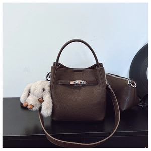 Détail du sac seau en cuir grainé marron foncé avec fermoir argenté et breloque lapin en peluche