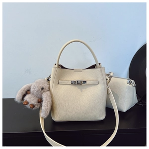 Détail d'un sac seau beige texture lychee avec boucle en métal et charm lapin mignon