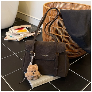 Détail du sac fourre-tout en daim marron avec deux sangles et pendentif chien en peluche