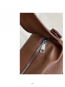 Primer plano de la cremallera de metal plateado y la textura de cuero marrón del bolso