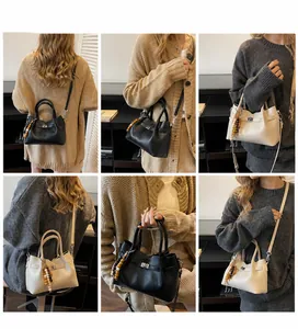 Détail d'un sac seau vintage avec texture litchi, fermoir en métal et pendentif perlé