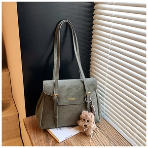 Détail du sac cabas vintage vert sauge avec finitions dorées et breloque chiot en peluche