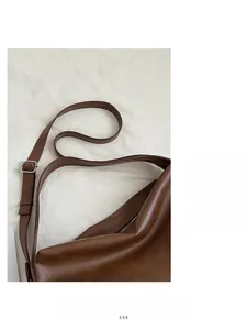 Detalle de correa de cuero ajustable y hebilla de metal plateado en un bolso marrón