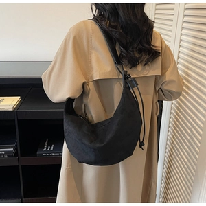 Detail view of the sleek black suede crescent shoulder bag with drawstring accents