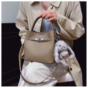 Détail d'un sac seau en cuir taupe avec fermoir métallique et breloque lapin en peluche