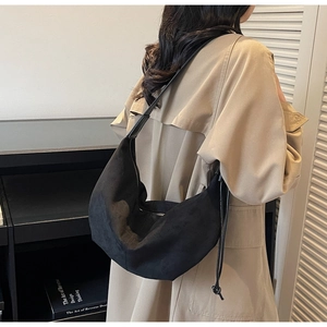 Detail of minimalist black suede crescent shoulder bag with drawstring side and matte finish