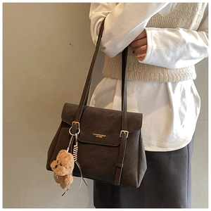 Détail du sac cabas en cuir marron foncé avec boucles dorées et breloque ourson