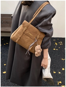 Gros plan d'un sac cabas marron vintage avec pendentif ours et ruban en soie