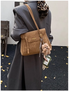 Détail d'un sac cabas marron en daim avec lettrage doré et porte-clés chien en peluche