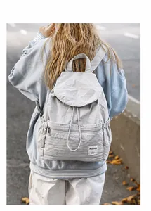 Vue extérieure d'un sac à dos en nylon gris clair avec cordon et étiquette de marque