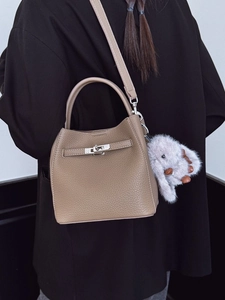 Sac seau minimaliste en cuir beige avec boucle métallique et breloque lapin en peluche