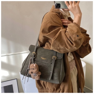 Détail du sac cabas en cuir vert foncé avec rabat et breloque ours en peluche mignonne