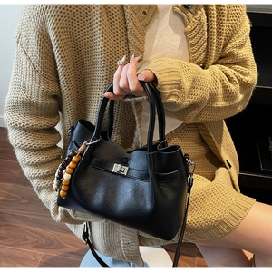 Détail de la texture en cuir grainé noir et du fermoir rotatif argenté du sac seau