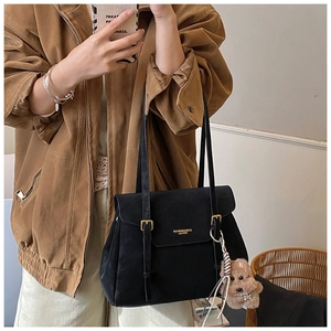 Détail du sac cabas en daim noir avec boucles en métal et un pendentif peluche chien