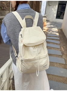 Gros plan d'un sac à dos en nylon beige avec cordon de serrage et rabat supérieur