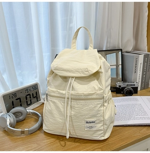 Détail du sac à dos en nylon blanc crème avec cordon de serrage sur table en bois