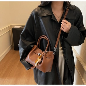 Gros plan du sac seau en cuir marron avec perles en bois et fermoir en métal argenté