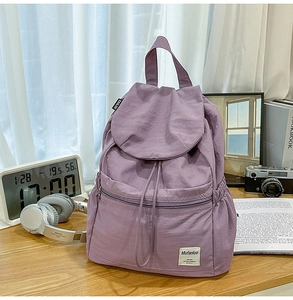 Détail d'un sac à dos violet en nylon avec fermeture à cordon et étiquette de marque