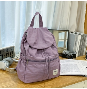 Détail du sac à dos en nylon violet avec fermeture à rabat et poche avant zippée