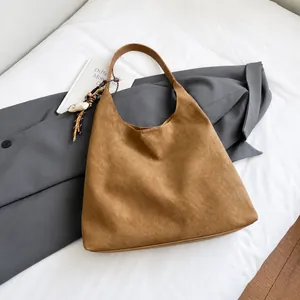 Close-up of caramel suede tote bag featuring a textured finish and ethnic woven tassel charm