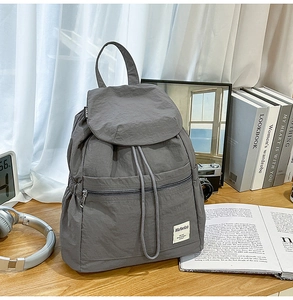 Détail d'un sac à dos gris en nylon avec cordon, rabat et poche avant zippée pratique