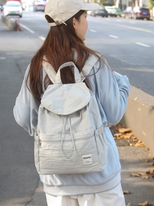 Sac à dos minimaliste en nylon gris clair avec fermeture à cordon porté à l'extérieur