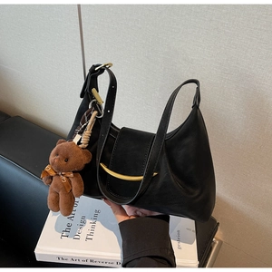 Detail view of black matte leather bag with golden moon buckle and teddy bear charm