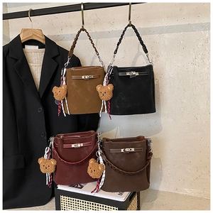 Detailed view of four colorful suede bucket bags with woven handles and teddy bear charms