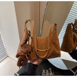 Detail of a brown Hobo bag featuring golden hardware and a cute plush bear charm