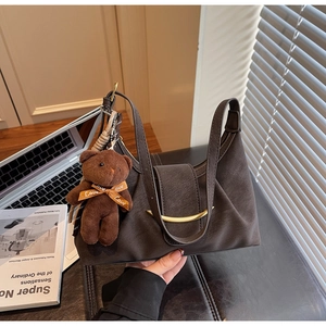 Detail of vintage brown leather dumpling bag with golden metal buckle and bear charm