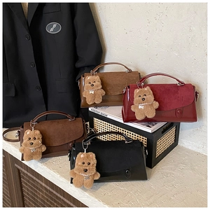 Detailansicht von matten Kunstledertaschen mit Bärenanhänger für den Büroalltag