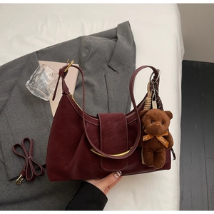 Detail of burgundy dumpling bag with gold hardware, plush bear charm and silk scarf handle