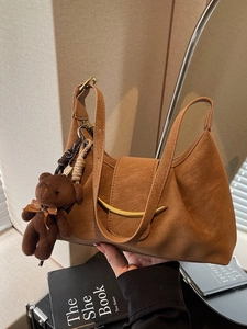 Minimalist caramel moon bag with gold buckle and plush bear charm in a modern setting