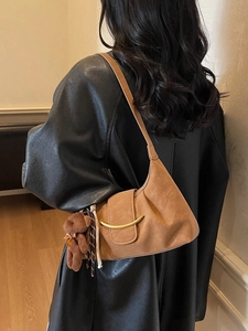Retro brown hobo dumpling bag with crescent buckle and plush bear charm on a model