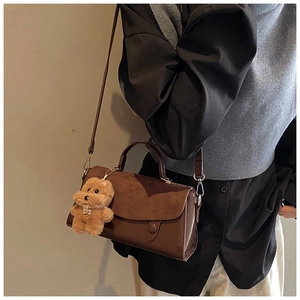 Detail einer braunen Umhängetasche mit Texturmix und niedlichem Hundeanhänger