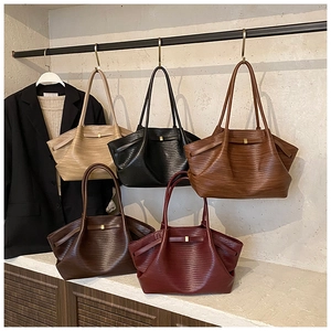 Detail view of woven leather tote bags in five earthy tones with long shoulder straps