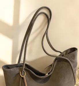 Detail view of durable slim leather handles and metal hardware on large brown tote bag